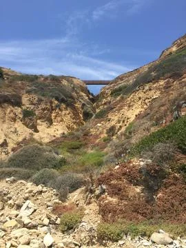 Vibrant Coastal Cliffs Under a Clear Blue Sky With a Bridge Above Stock Photos