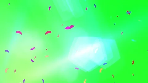 Vibrant confetti particles falling against bright green background with glowing 스톡 동영상 335280868