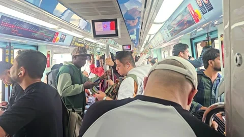 A vibrant, crowded interior of a Dubai Metro carriage showcasing diverse passeng Stock Footage 328371354