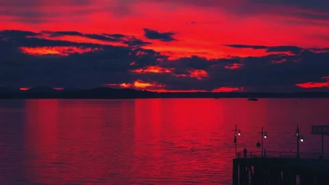 Vibrant dark red sunset dusk sky clouds flying over water aerial view Stock Footage 276608126