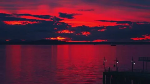 Vibrant dark red sunset dusk sky clouds flying over water aerial view Stock Footage 276659640
