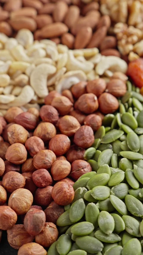 Vibrant display of almonds, cashews, walnuts, and dried apricots fills surface 스톡 동영상 292390605
