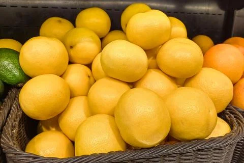 Vibrant display of fresh lemons in a rustic woven basket at a market 库存照片