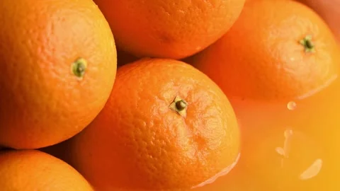 A vibrant drop of juice falls next to several ripe oranges Stockbeeldmateriaal 305669647