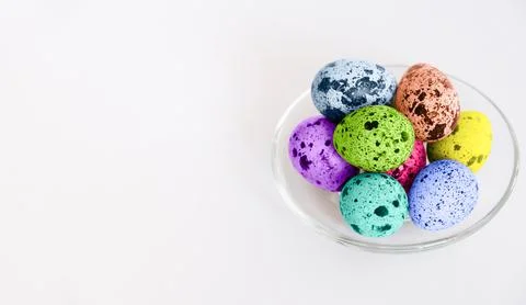 Vibrant Easter eggs with speckled patterns in a clear glass bowl Stock Photos
