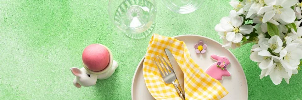 A vibrant Easter table setting features yellow checkered napkins wrapped with Stock Photos