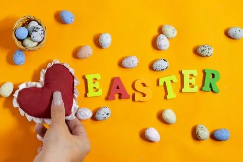 Vibrant Easter-themed arrangement featuring a hand holding heart-shaped decorati Stock Photos