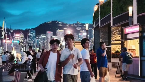 A vibrant evening scene at the Tsim Sha Tsui waterfront in Hong Kong, featuring Stock Footage 338280338