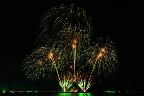 Vibrant Fireworks Exploding And Reflecting Over Calm Sea At Night Long Expo.. Стоковые фото