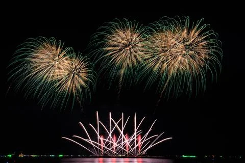 Vibrant Fireworks Exploding Over Ocean Water In Dark Night Sky Shot Stock Photos