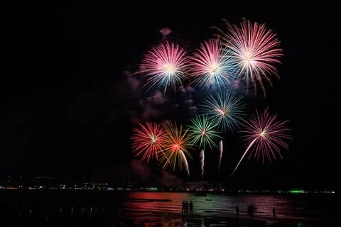 Vibrant Fireworks Exploding Over Silhouette Crowd At Beach In Pattaya Thail.. Stock Photos