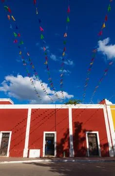 Vibrant flag chains over bright blue sky along red colonial building, Vall... Stock Photos
