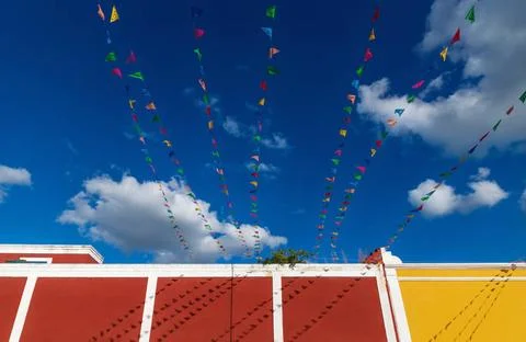 Vibrant flag chains over bright blue sky along colorful colonial building,... Stock Photos