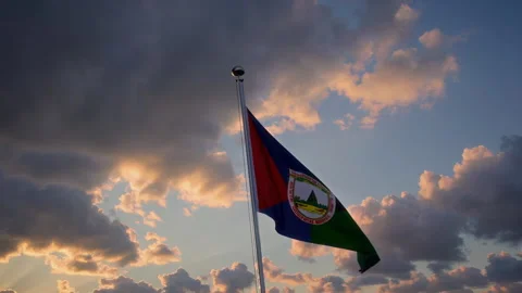 A vibrant flag waves against a dramatic sky with beautiful clouds, creating an Stock Footage 306177405