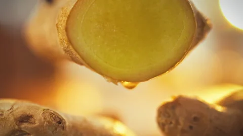 A vibrant ginger root is freshly sliced releasing a stream of pungent ginger Stock Footage 331315088
