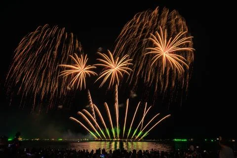 Vibrant Golden Fireworks Explode Over Dark Horizon With Spectators Silhouet.. Foto stock