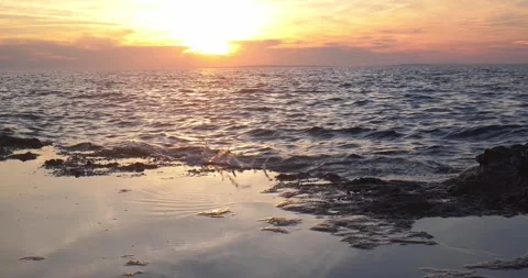 Vibrant golden sunset sky reflecting on rocky coastal water puddles Stock Footage 337418932