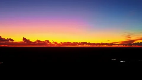 Vibrant gradient sunset sky with fiery orange, pink, and blue over dark Stock Footage 320887496