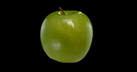 A vibrant green apple gracefully orbits against a dark. Stock Footage 300498950