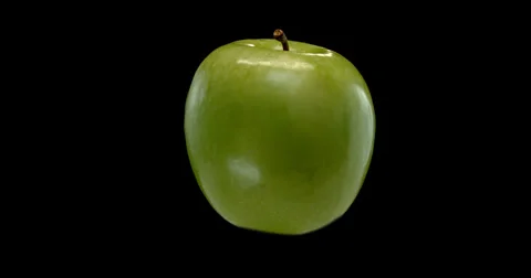 A vibrant green apple gracefully orbits against a dark. Stock Footage 300498974