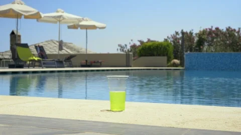A vibrant green drink in a plastic cup on the poolside, summer vibe Stock Footage 328664733
