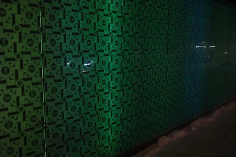 A vibrant green patterned wall shines at night. Stock Photos
