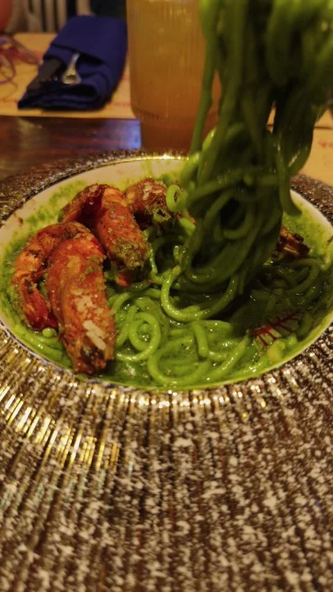Vibrant green spaghetti topped with large grilled prawns on an elegant plate, Stock Footage 344911089