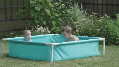 Vibrant greenery backyard two young boys swims in inflatable pool happy family Stock Footage 279566085