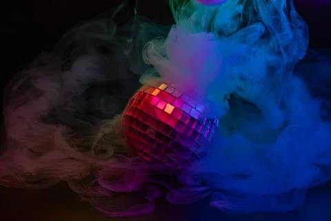 A vibrant image of a disco ball glowing with rainbow lights in the mist, evok Stock Photos