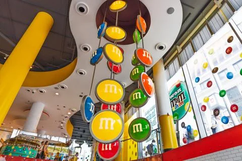 Vibrant M and M candy store interior with huge hanging logo discs. London, UK, 2 库存照片