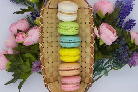 Vibrant Macarons in a Bamboo Tray Surrounded by Floral Blooms Stock Photos