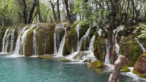 Vibrant Mossy Waterfall Flowing into Turquoise Lake, Jiuzhaigou Valley, Sichuan Stockbeeldmateriaal 337007364