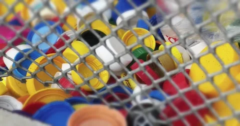 Vibrant, multi-colored plastic caps collected for recycling, visible through  Video stock 292688063