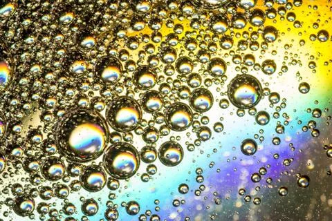 Vibrant multi-coloured bubbles form a psychedelic oil on water abstract backg Stock Photos