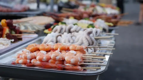 A vibrant night market stall featuring fresh shrimp and squid skewers. The mix Stock Footage 309933763