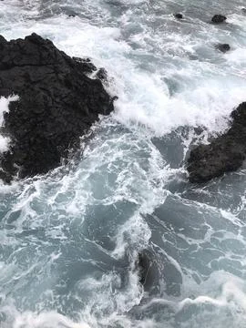 Vibrant ocean waves are dramatically colliding with rugged rocks, creating a  Stock Photos