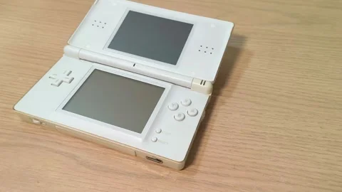 Vibrant old white portable handheld video gaming console on a wooden table, Video stock 318310937