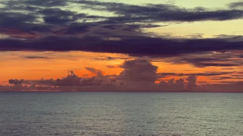 Vibrant orange and dark clouds glow over a tranquil ocean at sunset, captur.. Stock Footage 338281702