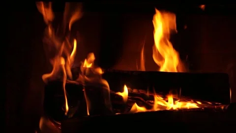 Vibrant orange flames burning brightly in a dark fireplace Stock Footage 324124957