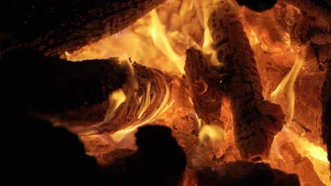 Vibrant orange flames dance and flicker through burning logs in a cozy, warm Stock Footage 339676653