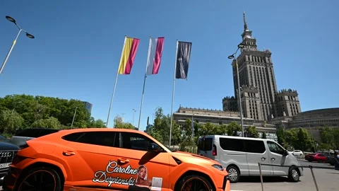 Vibrant Orange Lamborghini Urus Parked in Front of Iconic Palace of Culture.. Stock Footage 313269040