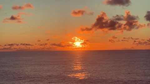 Vibrant orange sunset over the ocean with sun dipping below the horizon and.. Stock Footage 338282016