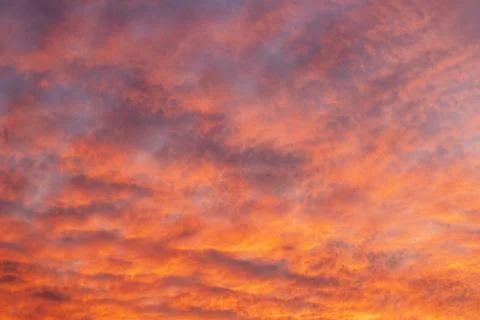 Vibrant orange sunset sky with dramatic clouds and warm painterly tones across Stock Photos