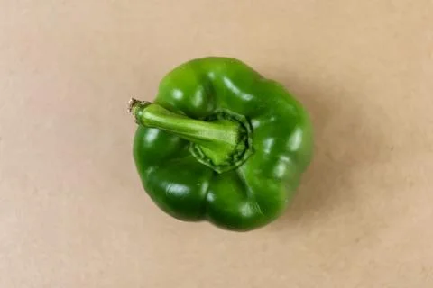 A vibrant overhead shot capturing a single green bell pepper placed centrally Stock Photos