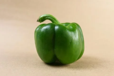 A vibrant overhead shot capturing a single green bell pepper placed centrally Stock Photos