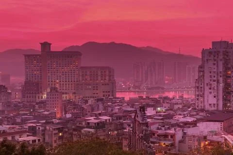 Vibrant pink sunset over a distant cityscape with mountains Stock Photos