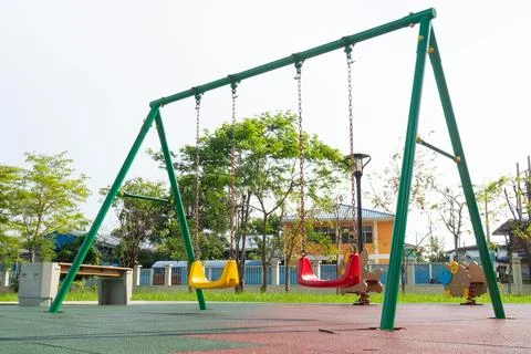 A vibrant playground scene featuring green swing set with red and yellow swin Stock Photos