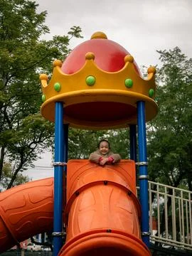 Vibrant playground slide features a red dome crown with yellow and green jewe Stock Photos