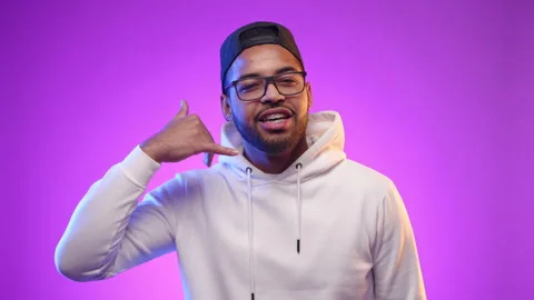 Vibrant Portrait of Young Man Gesturing Call Me Sign with Joyful Expression Stock Footage 270704752