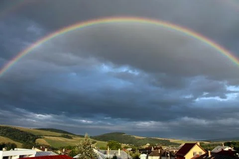 Vibrant rainbow arching across a dramatic cloudy sky Stock Photos